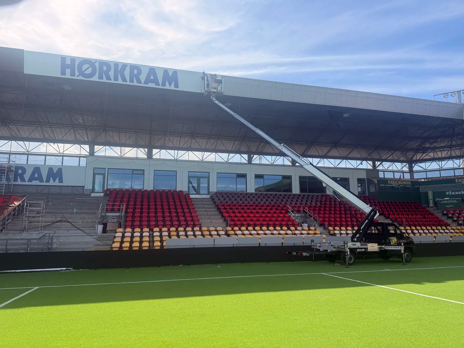 Montage af Hørkram-banner fra lift på tagkanten af stadiontribunen