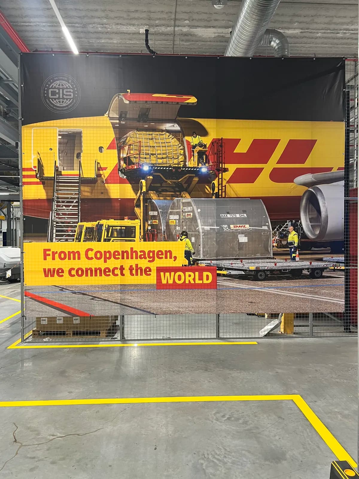 Stort DHL-banner med fragtfly og teksten From Copenhagen, we connect the World monteret i logistikcenter