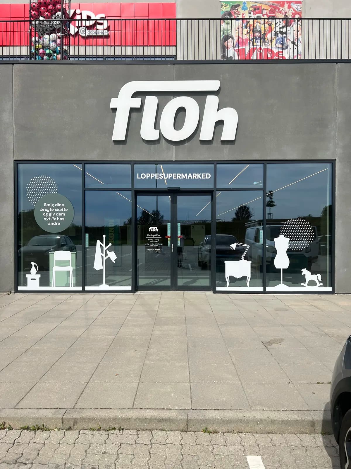 Hvide 3D-facadebogstaver til Floh monteret på betonfacade med tilhørende foliedekoration på vinduespartierne
