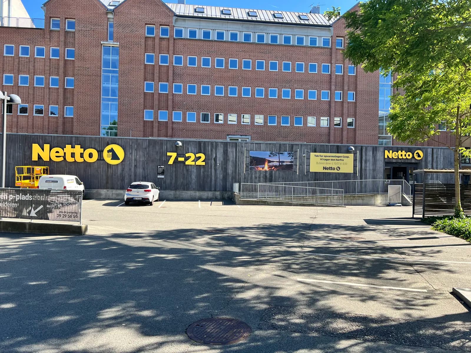 Facadebogstaver, logoskilte og åbningstider til Netto monteret på lang træbeklædt facade