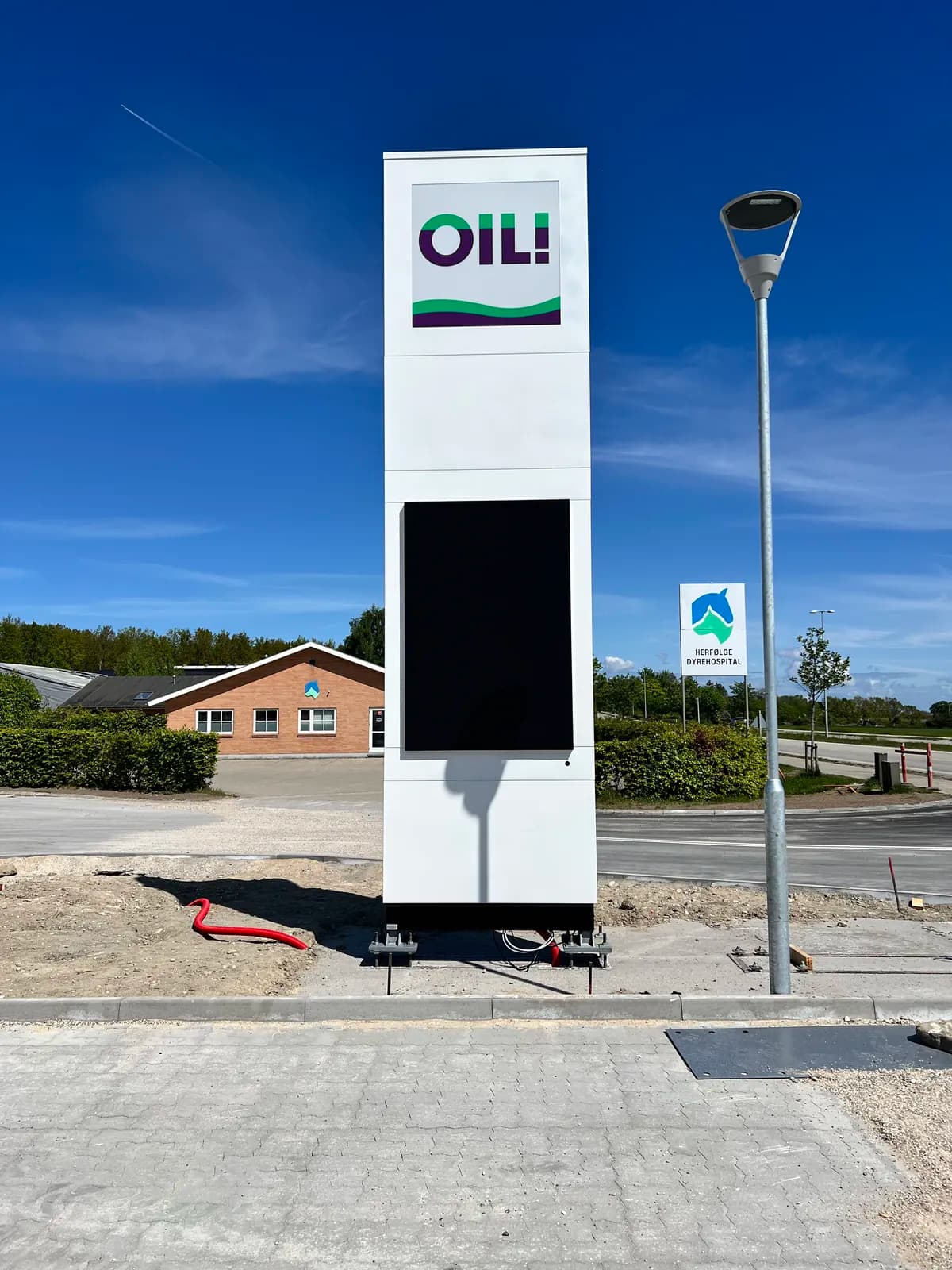Hvid pylon med logo og digital prisskærm til OIL! tankstation under etablering