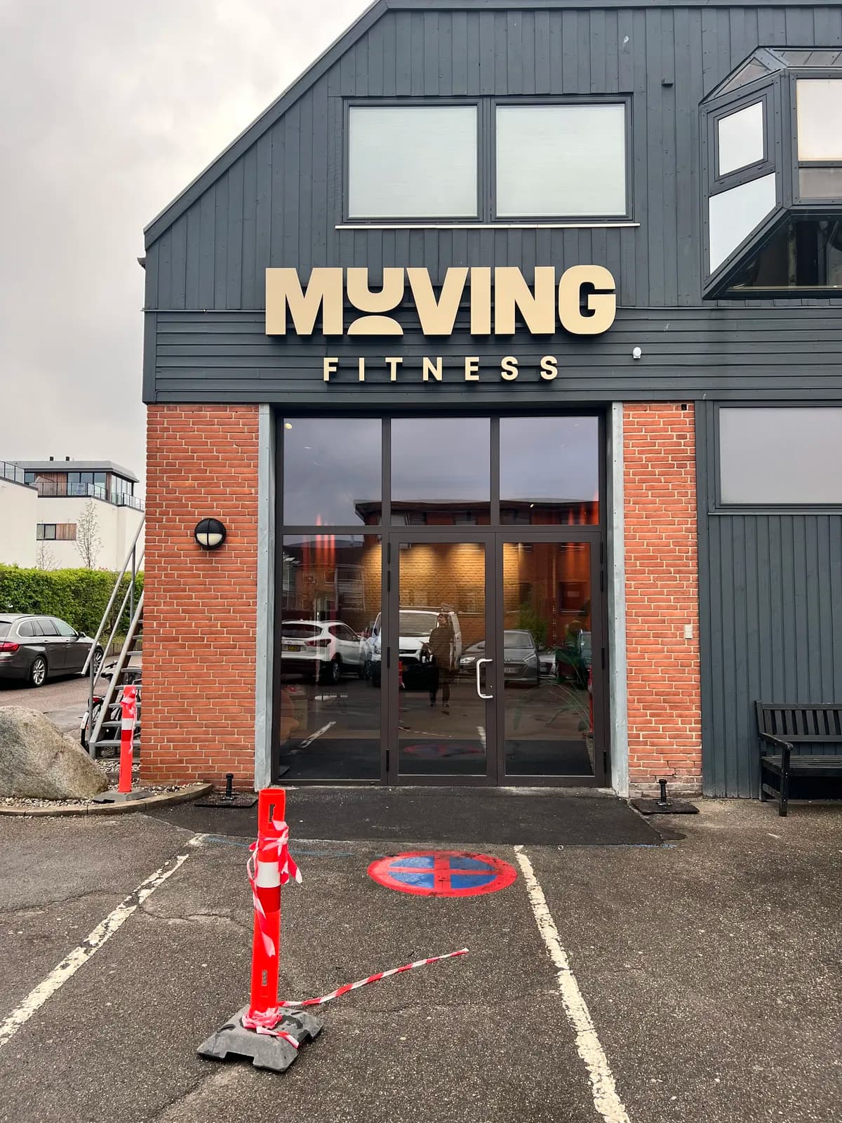 Facadebogstaver til Muving Fitness over indgangspartiet på sortmalet træfacade