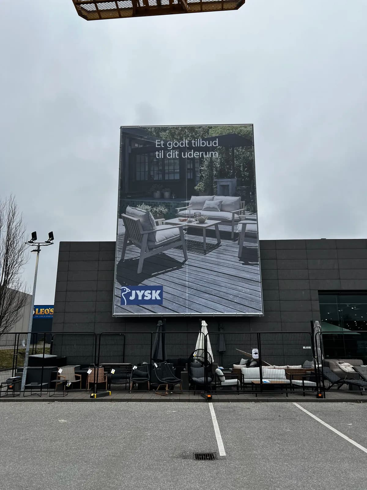 Stort reklamebanner til JYSK monteret på facaderamme med kampagne for udemøbler