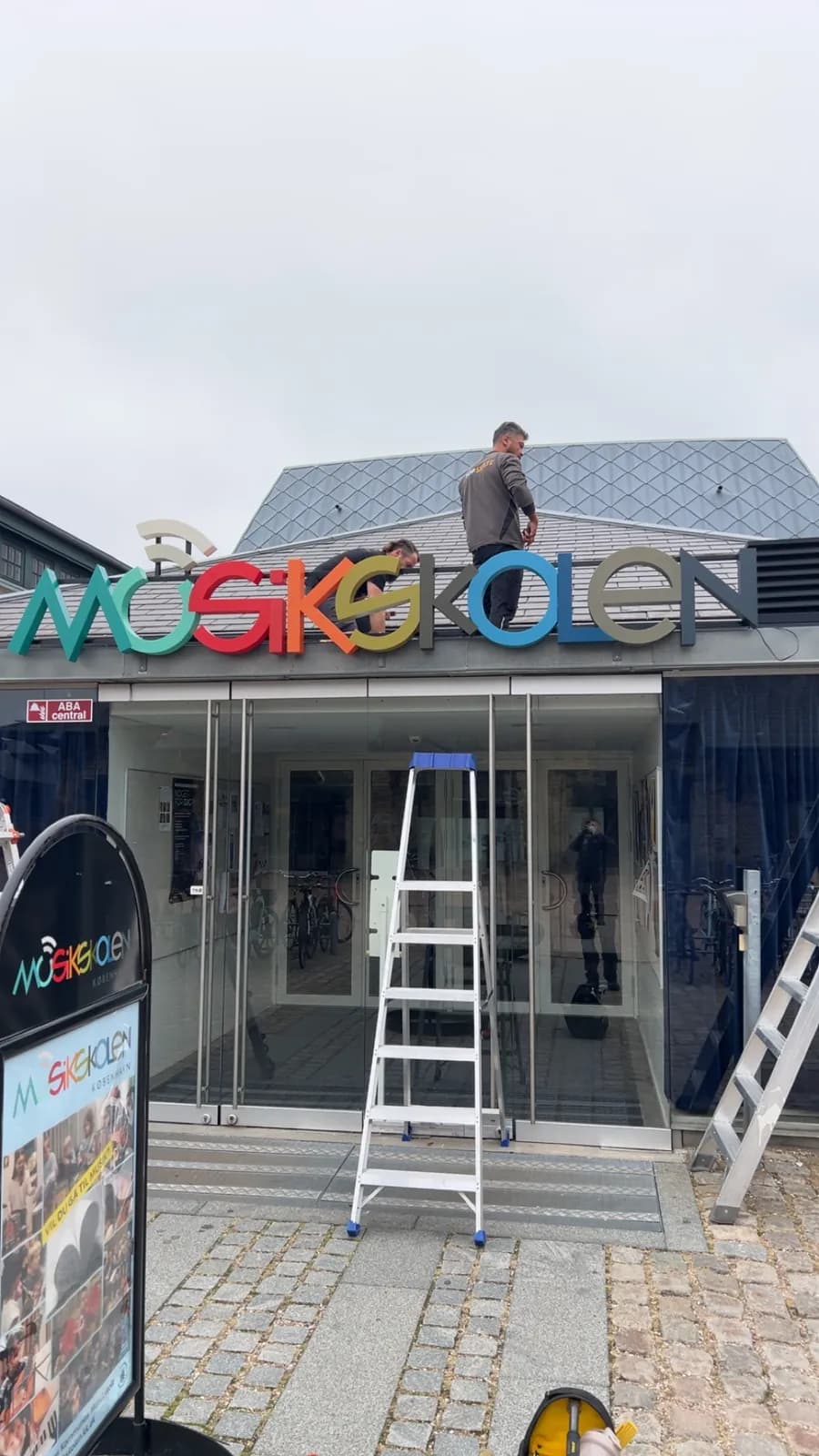 Montage af farverige facadebogstaver til Musikskolen København over indgangspartiet