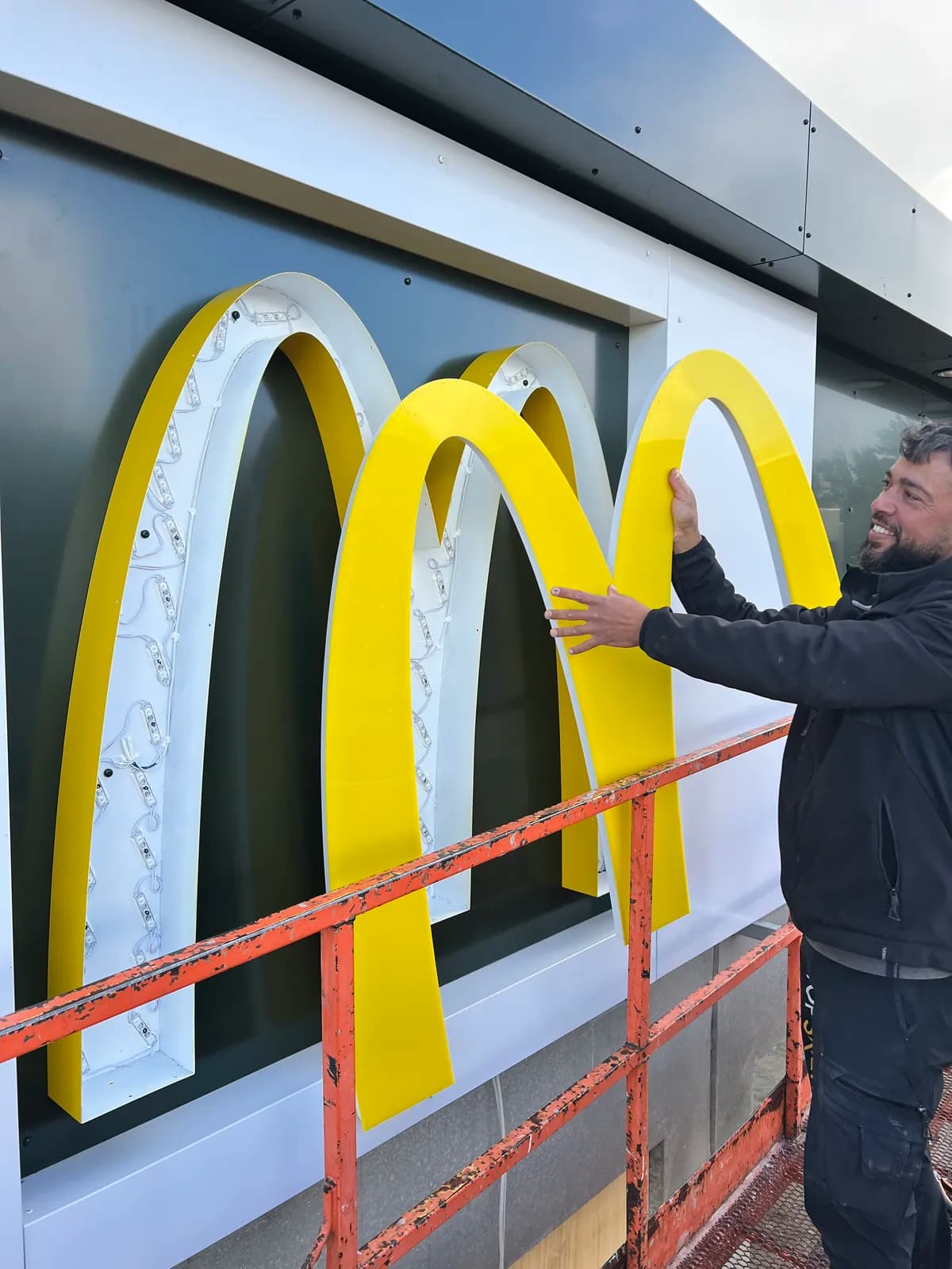 Montør tilpasser LED-belyste logobogstaver til McDonald's på facaden