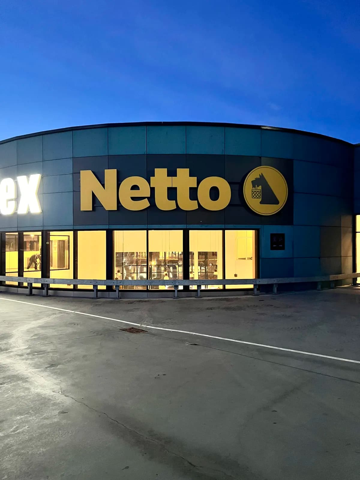 Nymonteret Netto-facadeskilt fotograferet ved skumring med oplyst butik
