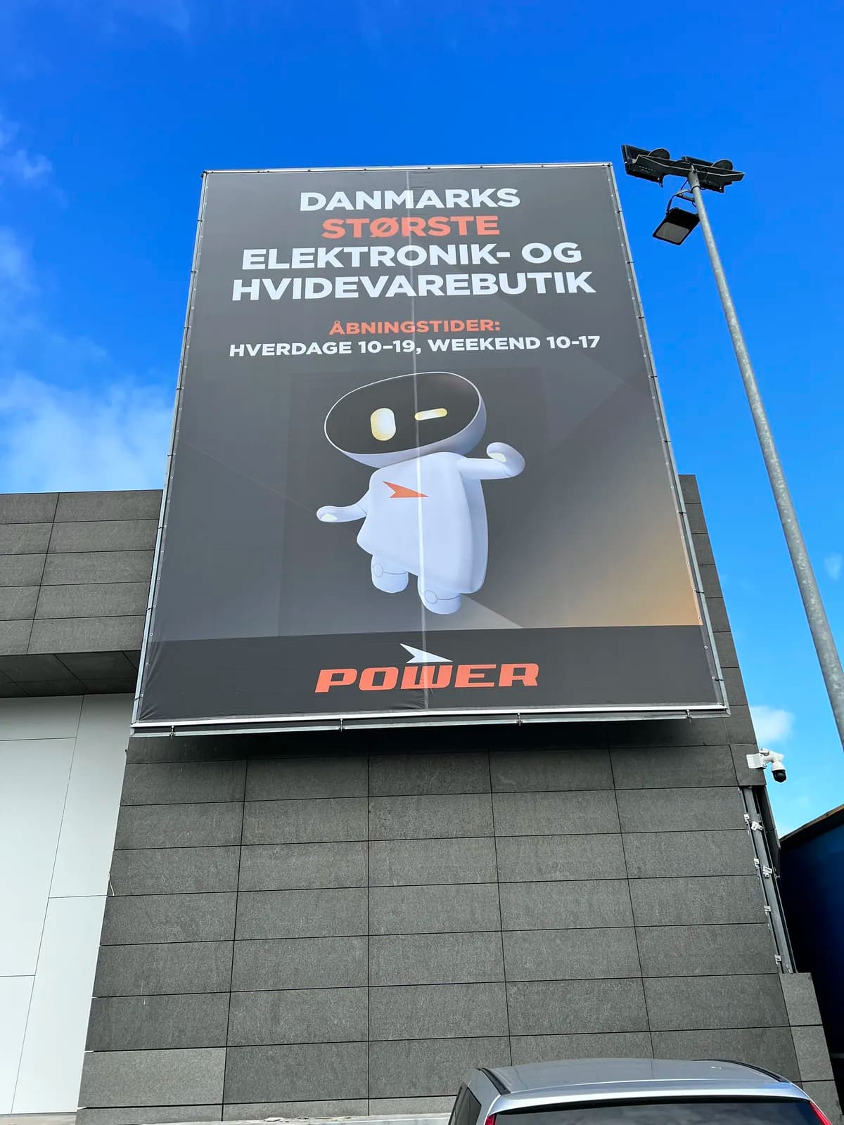 Stort facademonteret reklamebanner med kampagnegrafik hos Power