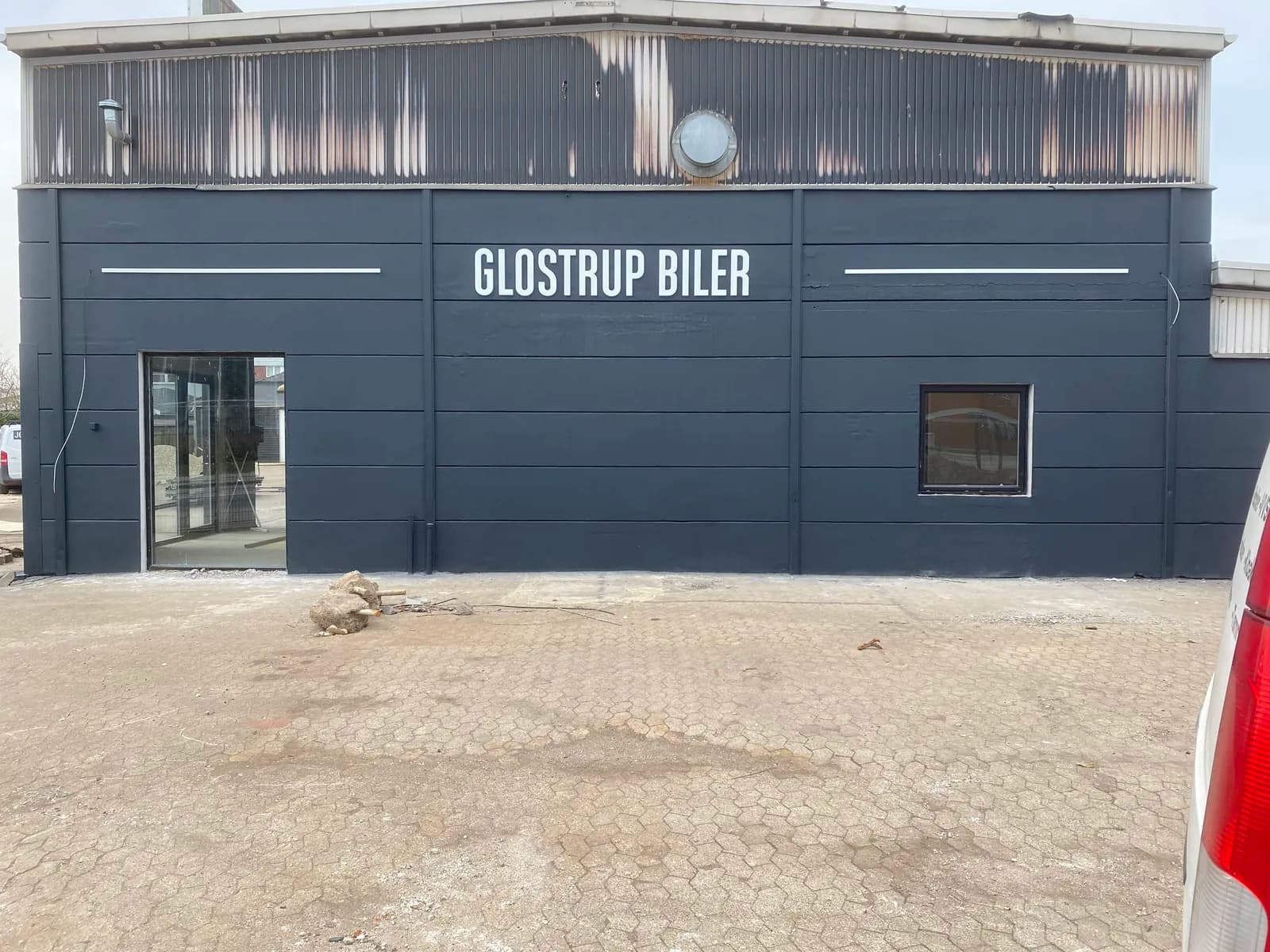 Hvide facadebogstaver monteret på mørk facade hos Glostrup Biler