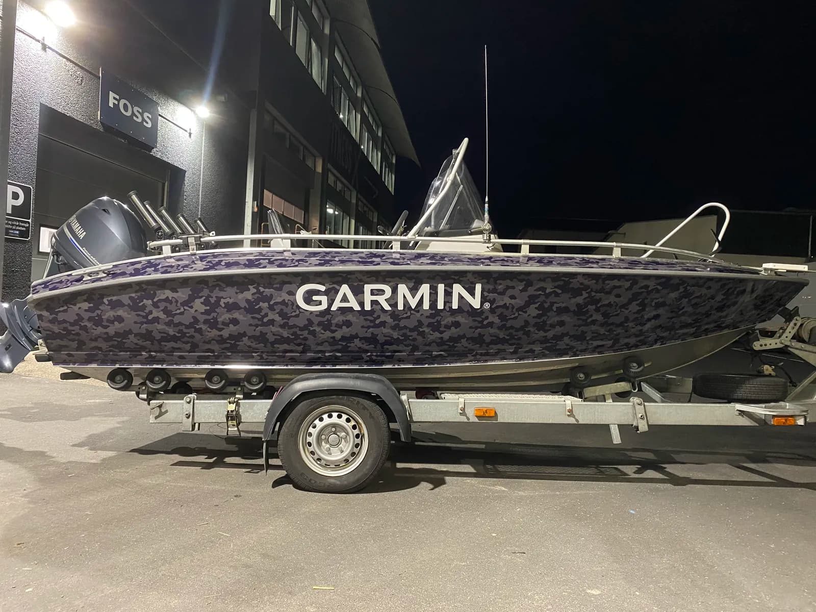Helfoliering af Garmin-fiskebåd i mørkeblåt camouflagemønster med hvidt logo, fotograferet om aftenen